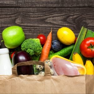 Paper grocery bag full of different healthy food: Vegetables, dairy, meats, breads