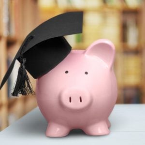 Piggy Bank with Graduation Hat on with books in the background to illustrate financial literacy.