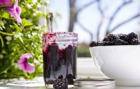 Black raspberry jam in a glass jar by the window.
