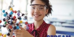 Middle school aged girl holds a scientific model while wearing safety glasses.