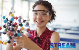 Middle school aged girl holds a scientific model while wearing safety glasses.