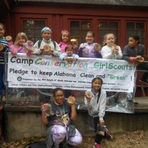 Girl Scouts pose beside the Camp Conservation Banner