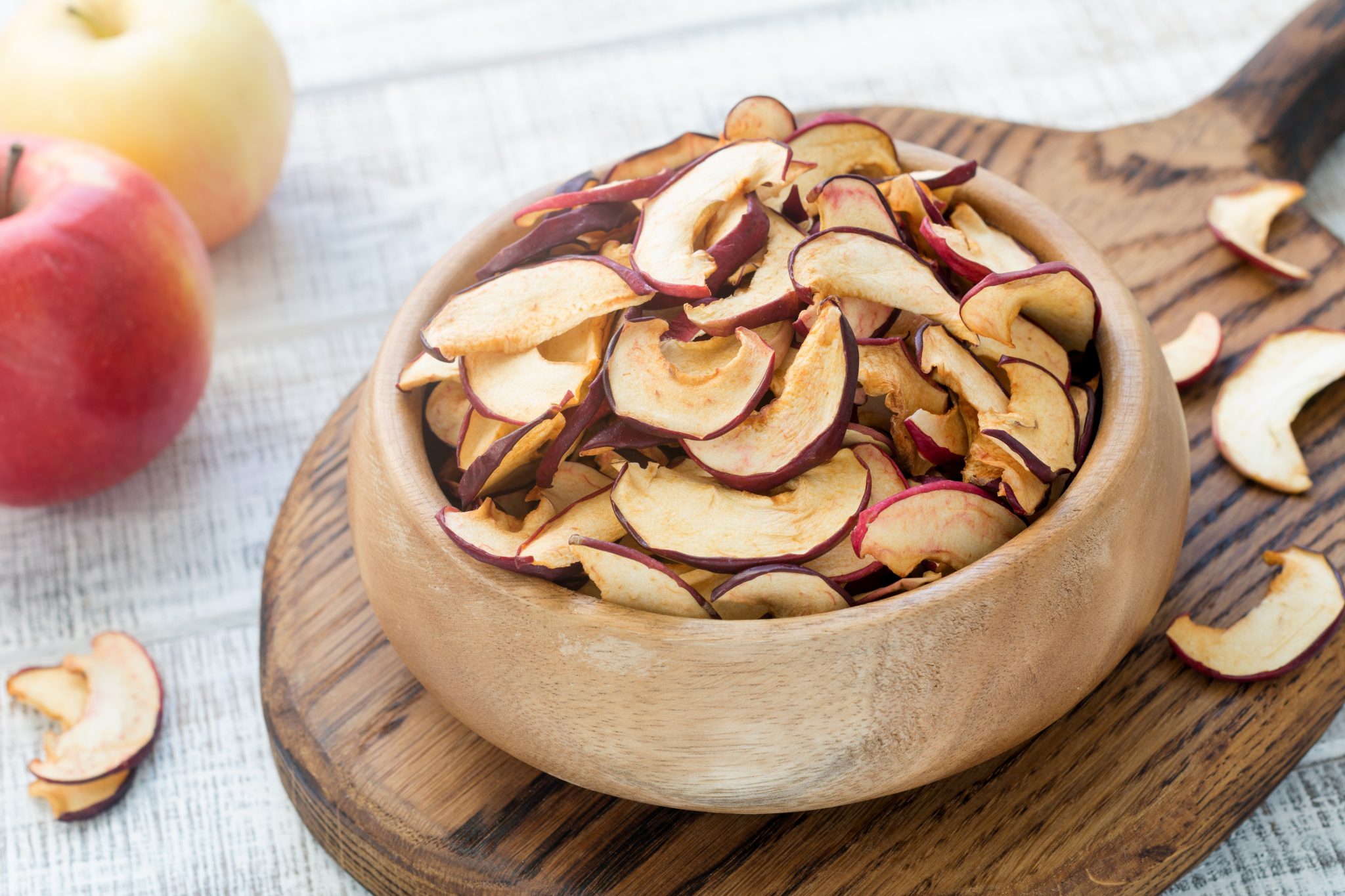 Homemade dried apples or apple chips in a wooden bowl, closeup view