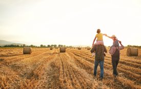A family walking through a hay field.