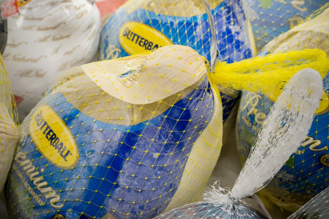 Several frozen turkeys in a grocery store.