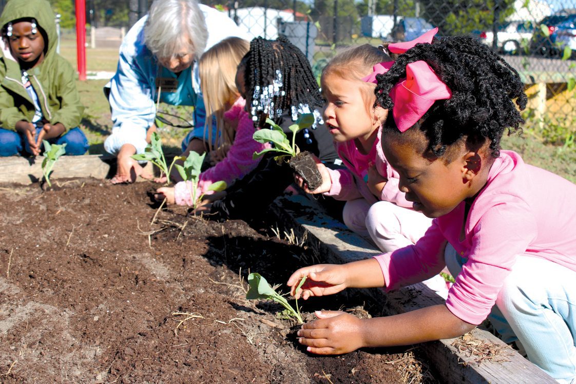 Young students planting in a raised bed