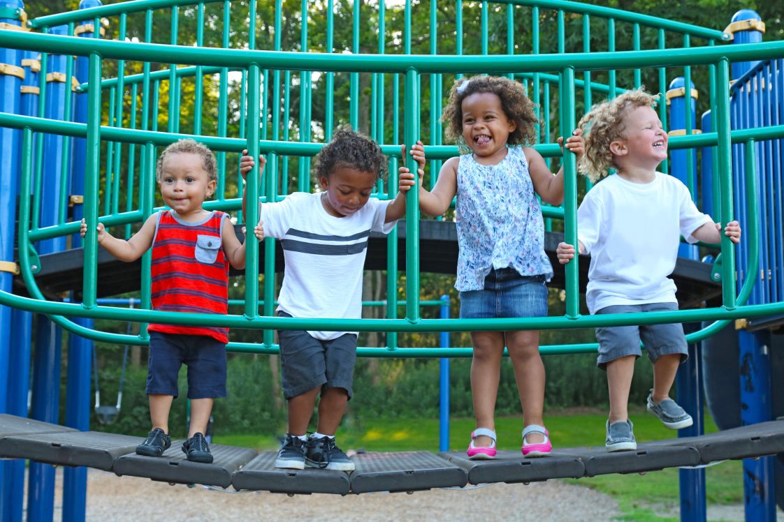 A group of young children playing on a play ground in a park.