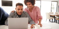 A Black mother and her son looking at a laptop.