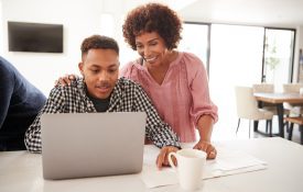 A Black mother and her son looking at a laptop.