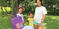 A young mother standing outside with her two daughters.