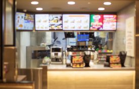 A blurred image of a fast-food restaurant counter and menu board.