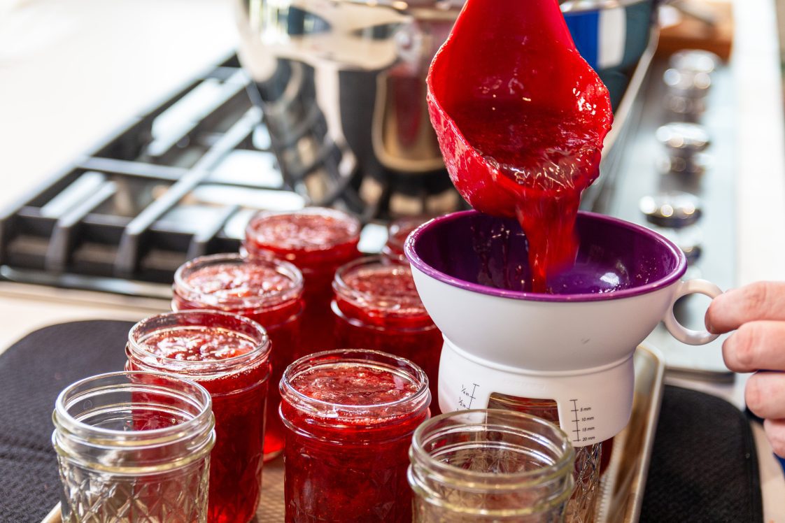 using home food preservation methods and ladling jam into jars