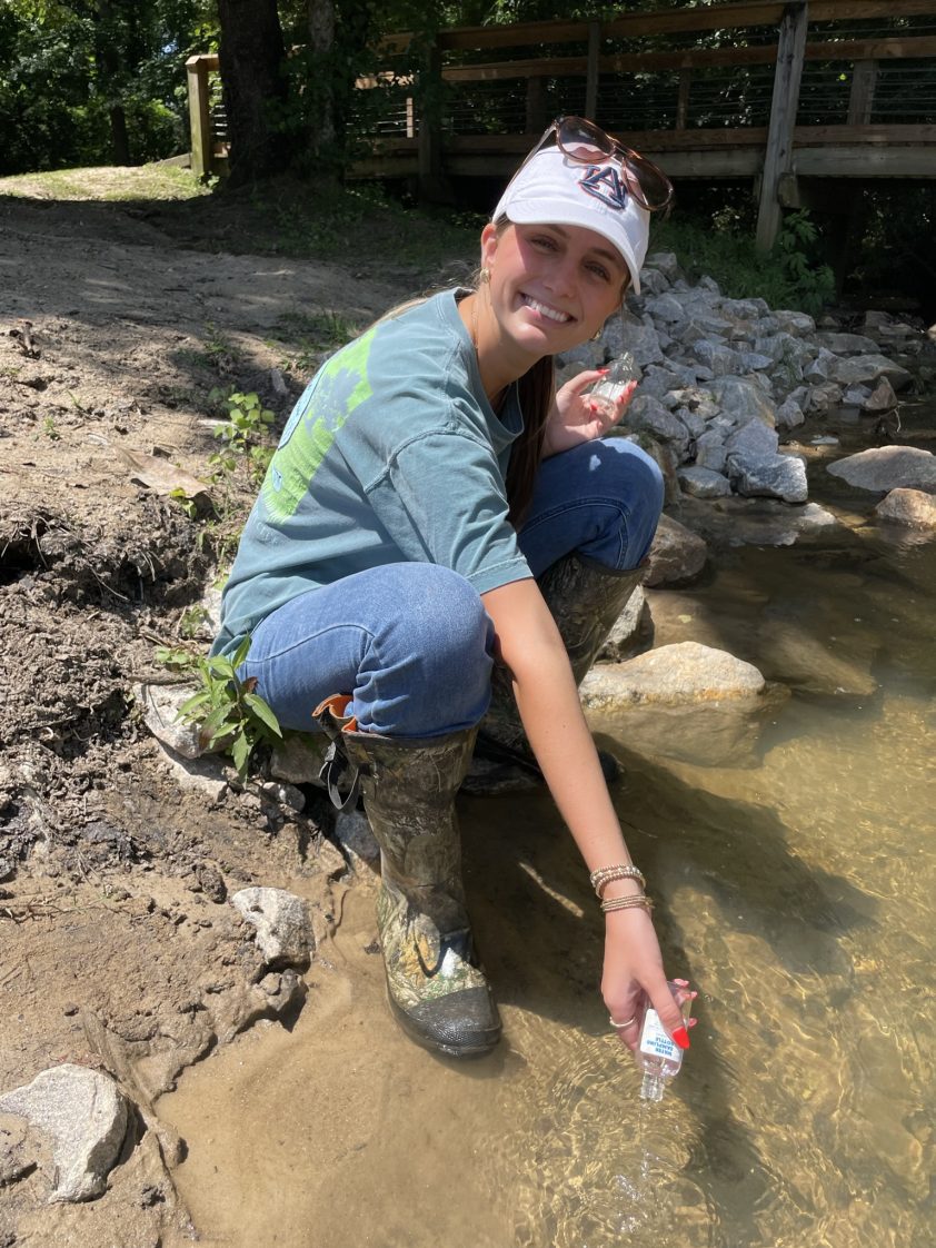 Emily Ward collecting water samples for testing in Town Creek.