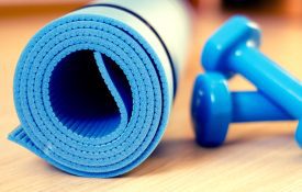 A yoga mat and dumbbells for a fitness class.