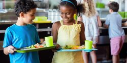 School children holding food tray in a cafeteria.