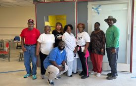 A group of people standing in front of the Boligee OnMed Care Station.