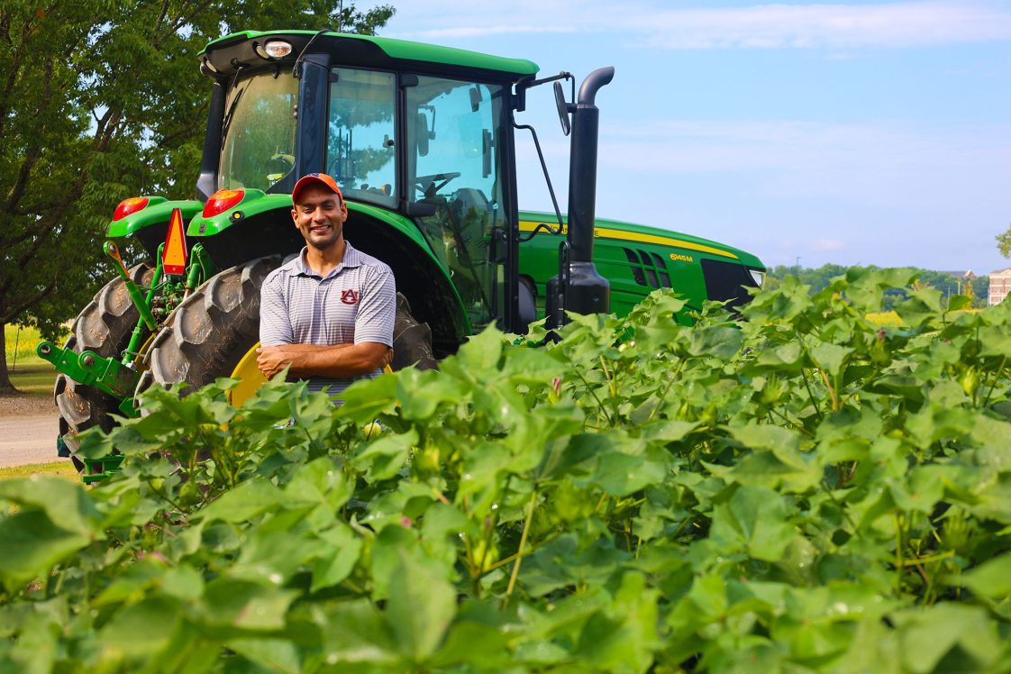 Simer Virk standing in a field near a tractor.