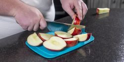 A person cutting apples in a kitchen.