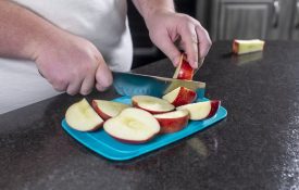 A person cutting apples in a kitchen.