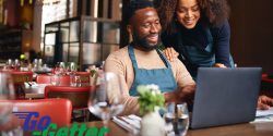 Two African American entrepreneurs sit at a table in their business looking at a computer monitor.