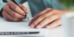 A close up of a man's hands signing documents.