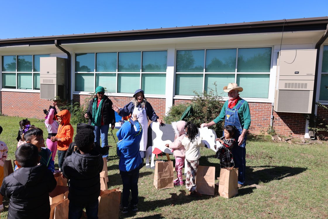 A group of children listening to adults talk about dairy cows at the Farmers Walk event.