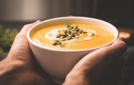 person's hand holding a cup of winter soup