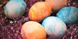 Dyed Easter eggs in a basket of fake grass.