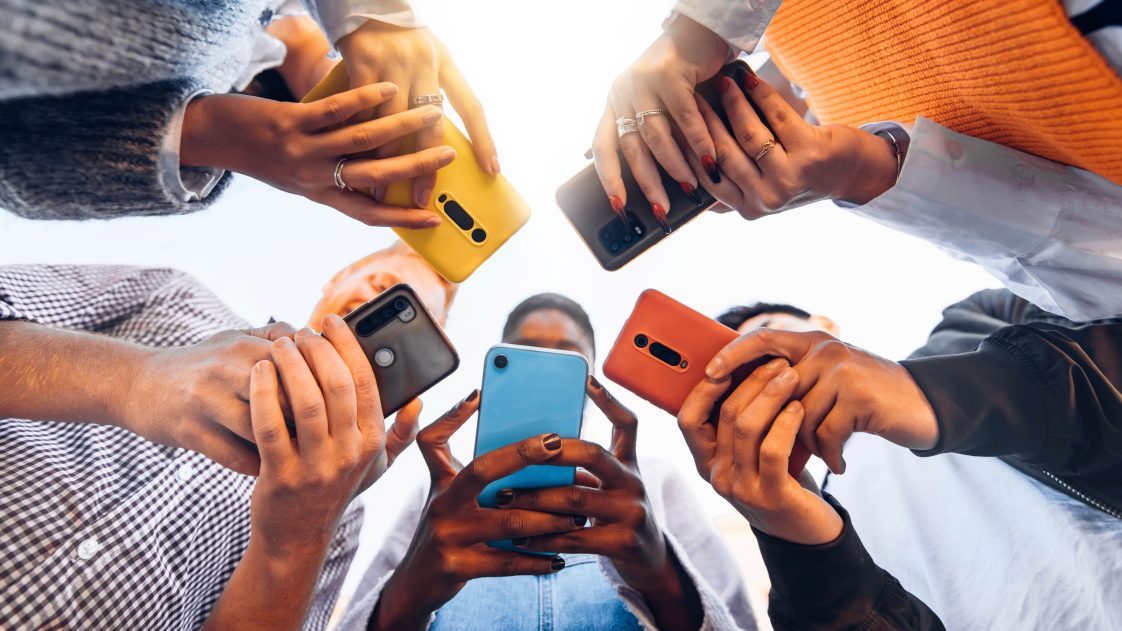 teens standing in a circle using cell phones